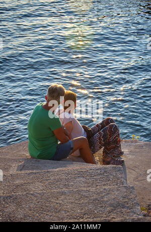 Zwei reife Frauen sitzen am Meer Sonnenuntergang beobachten Stockfoto