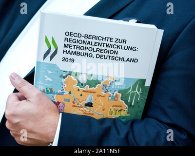 23. September 2019, Niedersachsen, Seevetal: Ein Mann hält einen OECD-Bericht über die Entwicklung der Metropolregion Hamburg in seine Arme. In seinen Berichten, die OECD gibt mehr als 50 konkrete Empfehlungen für Maßnahmen in den sechs vorrangigen Bereichen der Innovation, Bildung und Facharbeiter, Digitalisierung, Wohnungsbau und Verkehr Planung, erneuerbare Energien sowie kulturelle und touristische Vermarktung. (Auf dpa' OECD gibt Empfehlungen für die Entwicklung der Metropolregion Hamburg") Foto: Daniel Bockwoldt/dpa Stockfoto