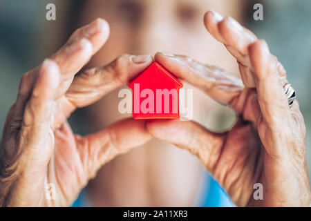 Ältere Frau mit einem kleinen Haus in Ihren Händen Stockfoto