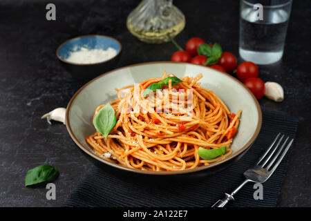 Nahaufnahme von Spaghetti in Tomatensauce auf schwarzem Hintergrund Stockfoto