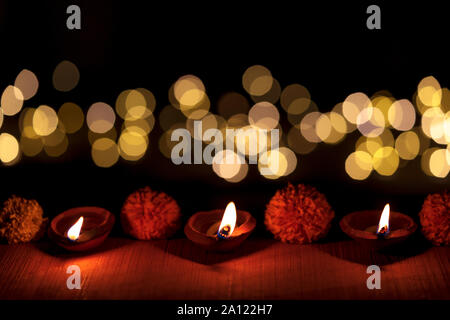 Dunkle moody Diya oder Terracotta Lampe leuchtet in einer Reihe während Diwali indischer Hindu Festival mit bokeh Licht isoltaed auf schwarzem Hintergrund. Stockfoto