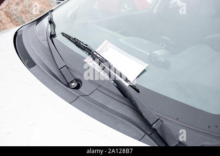 Nahaufnahme eines Parktickets auf der Außenseite der Windschutzscheibe des Autos unter dem Scheibenwischer. Stockfoto