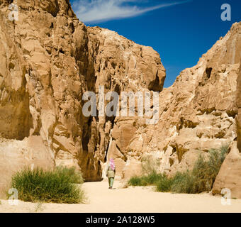 Beduinen in Weiß geht in der Schlucht in der Wüste zwischen den Felsen Stockfoto