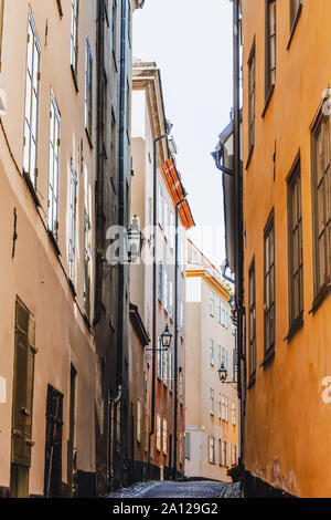 Blick von unten auf den Dächern eines gemütlichen engen mittelalterlichen Straße gelb orange rot Gebäude Fassaden in Gamla Stan, der Altstadt von Stockholm, Schweden mit Br Stockfoto