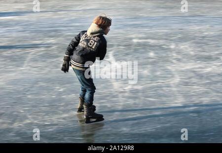 Junge Schlittschuhlaufen auf Natureis Stockfoto