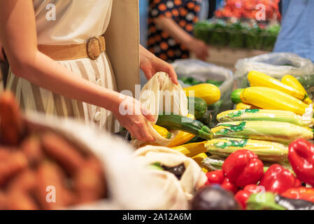 Null Abfall, Kunststoff Konzept. Nachhaltiger Lebensstil. Frau entscheidet, Früchte und Gemüse zu Farmers Market. Wiederverwendbare Baumwolle und Mesh eco Beutel für Stockfoto