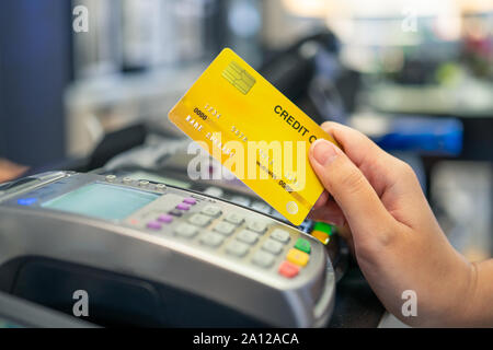 Kreditkarte streichen Maschine und eine junge Frau, die eine Kreditkarte für Einkäufe mit Geld von der Karte zu bezahlen. Oder Ratenzahlung Stockfoto