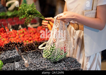 Null Abfall, Kunststoff Konzept. Nachhaltiger Lebensstil. Frau entscheidet, Früchte und Gemüse zu Farmers Market. Wiederverwendbare Baumwolle und Mesh eco Beutel für Stockfoto