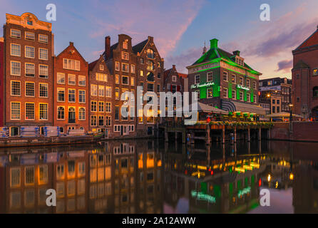 Ein Abend in Amsterdam, mit dem Blick auf die Heuschrecke und die Oude Kerk (Alte Kirche) im Hintergrund, das älteste Gebäude in Amsterdam. Stockfoto