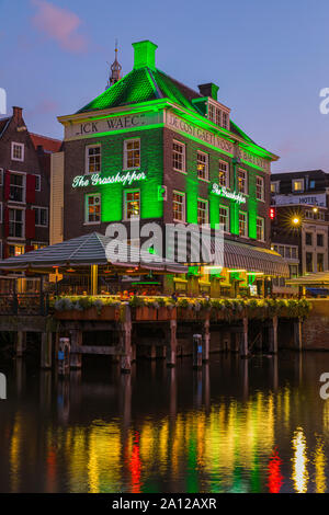 Ein Abend in Amsterdam, mit dem Blick auf die Heuschrecke und die Oude Kerk (Alte Kirche) im Hintergrund, das älteste Gebäude in Amsterdam. Stockfoto