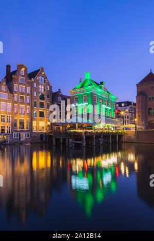 Ein Abend in Amsterdam, mit dem Blick auf die Heuschrecke und die Oude Kerk (Alte Kirche) im Hintergrund, das älteste Gebäude in Amsterdam. Stockfoto