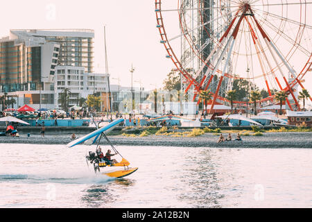 Batumi, Adscharien, Georgien - 10. September 2017: motorisierte Hängegleiter mit muslimischen Frau Landung auf dem Meer in der Nähe von Riesenrad im sonnigen Sommer Abend Stockfoto