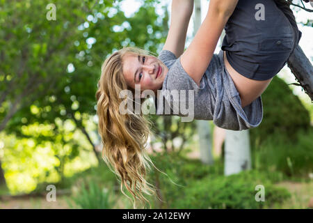 Der 13 Jahre alte Mädchen hing kopfüber vom Baum Stockfoto