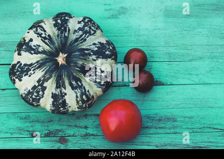 Stillleben mit August Ernte. Kürbis und Tomaten auf vintage Holz- Hintergrund. Das Konzept der Umweltfreundliche, organisches Gemüse, richtige Ernährung, Vegetarismus Stockfoto