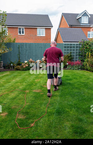 Man mäht seinen Rasen mit einem Speer und Jackson elektrische Rasenmäher (zurück in die Kamera) Stockfoto