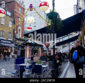 Londonern und Touristen Essen & Trinken ausserhalb des Restaurants und Shop. St. Christopher's Place, trendige open air Shopping, Central London, Weihnachten Stockfoto