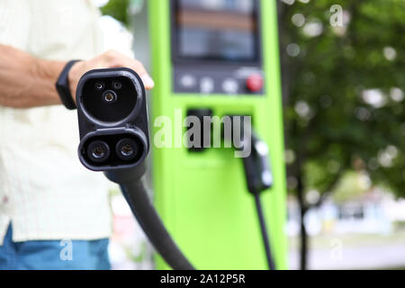 Mann, der das Ladekabel für Öko-Autos zeigt Stockfoto