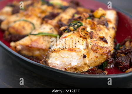 Sun-Dried Tomato Basil Mahi Mahi: eine Platte mit Mahi Mahi Filets mit Sonne gekrönt - getrocknete Tomaten, Basilikum, und Schalotten Stockfoto