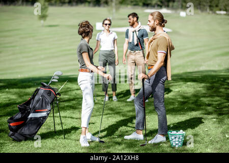 Junge elegante Freunde treffen auf dem Golfplatz vor dem Spiel, Spaß zusammen an einem sonnigen Tag Stockfoto