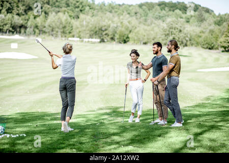 Gruppe von einem jungen Menschen lässig gekleidet, Golf spielen auf dem Golfplatz an einem sonnigen Tag Stockfoto