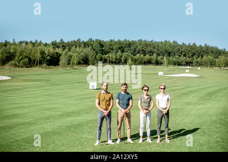 Portrait einer jungen Gruppe von Freunden stehen mit Golfausrüstung auf dem Golfkurs während eines Spiels an einem sonnigen Tag, breite Querformat Stockfoto