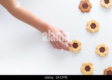 Die Hand des Kindes erreichen für hausgemachte Kekse, alle auf weißem Hintergrund. Für Text platzieren. Stockfoto