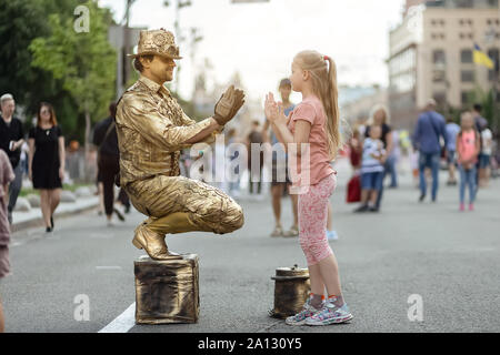 Kiew, Ukraine, 26. Mai 2019. Kleines Mädchen spielt Patty-kuchen spiel mit die lebende Statue street artist auf Khreshchatyk Straße Stockfoto