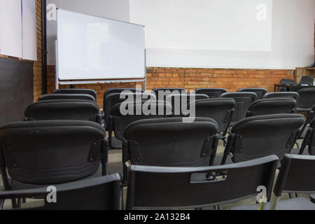 Leere Stühle Reihen vor white board und Wand angezeigt, bevor die Präsentation oder Seminar. Klassenzimmer oder Konferenzraum vor dem Öffnen mit keine Menschen. Stockfoto