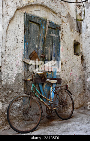 Altes, rostiges Fahrrad gegen einen verfallenen Marokkanischen Tür geparkt zu einem typischen Kalk getünchte Wand in die Quintessenz der Stadt Essaouira, Marokko, Afrika. Stockfoto