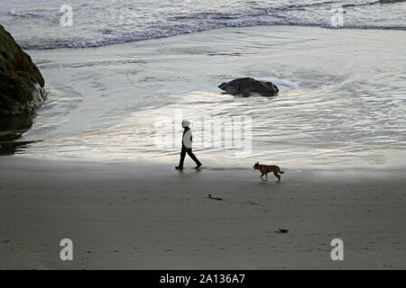 Ein Mann und sein Deutscher Schäferhund am Strand entlang der Pazifikküste Stadt Bandon, Oregon. Stockfoto