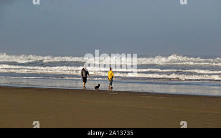 Ein Paar mittleren Alters und Ihren kleinen Hund wandern die leere Pacific Ocean Beach in Bandon, Oregon, entlang der Oregon Pazifikküste. Stockfoto