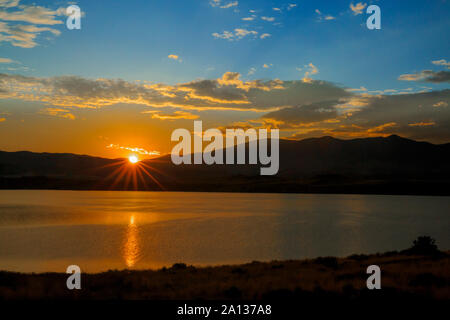 Sunburst flare der aufgehenden Sonne über dem Canyon Ferry Lake in der Nähe von Winston, Montana Stockfoto