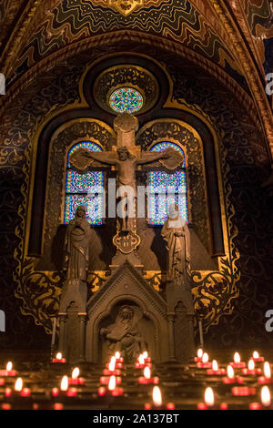 Statue von crusified Jesus in der Matthias Kirche mit angezündeten Kerzen auf einen Vordergrund. Stockfoto