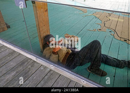 Ein obdachloser Mann schläft hinter einer Glasscheibe an einem öffentlichen Gehweg in Coos Bay, Oregon, entlang der Oregon Pazifikküste. Stockfoto