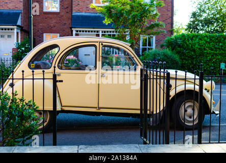 Die classic car Citroën 2CV neben einem malerischen Haus in England geparkt. Stockfoto