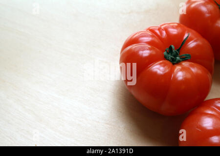 Große reife rote ganze Tomaten auf Schneidebrett Stockfoto