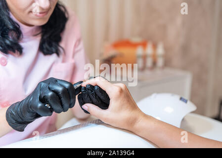 Maniküre. Professionelle Kosmetikerin macht Nägel reinigt mit nagelzange. Prozess hautnah. Frau im Beauty Salon. Schönheit und Pflege. Stockfoto