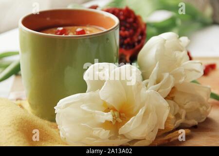 Zarte weiße Blume und Tasse Tee mit Granatapfel Stockfoto