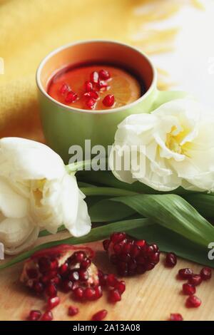 Zarte weiße Blume und Tasse Tee mit Granatapfel Stockfoto