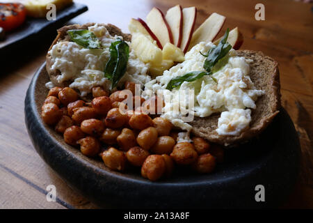 Gesund Stil, Englisches Frühstück mit Rührei Eiweiß auf Schwarzbrot, Kichererbsen, und Apple und Ananasscheiben auf rustics Holz Hintergrund Stockfoto