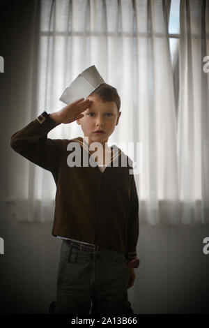 Vorderansicht eines entzückenden kleinen Junge mit seinen Händen in Salute angehoben. Stockfoto