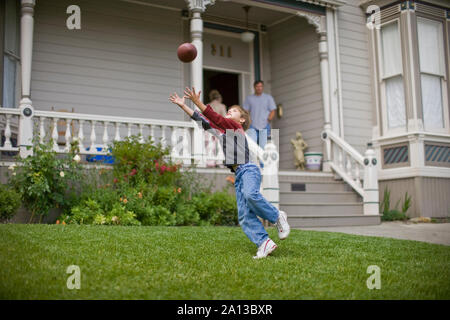 Junge bis ein Fußball im Vorgarten seines Hauses zu fangen. Stockfoto