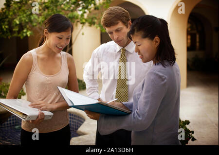 Eine Frau zeigt ihre zwei Kollegen die Dokumente in einer Datei. Stockfoto