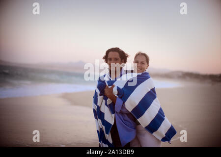 Ein Paar in einem blau-weiß gestreiften Handtuch schaut in die Kamera. Stockfoto