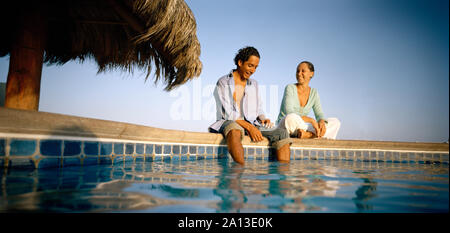 Ein paar genießt selbst sitzt in der Nähe des Pools. Stockfoto