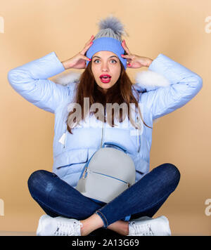 In Schock. Mädchen in aufgeblasen Mantel. fellimitat Mode. Grippe und der kalten Jahreszeit. Leder tasche Mode. Frau in Beanie-mütze mit Rucksack. happy Winterurlaub. warme Winterkleidung. einkaufen. Stockfoto