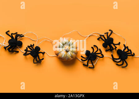 Halloween Dekorationen mit schwarzen Spinnen und Kürbis auf orangem Hintergrund. Flach, Ansicht von oben, kopieren. Banner. Stockfoto