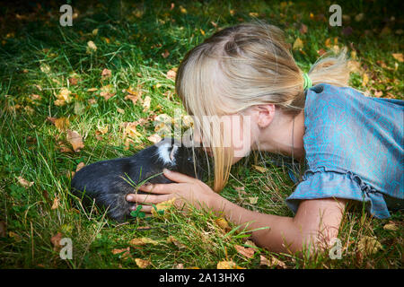 Kind nettes Mädchen spielen mit Haustier Meerschweinchen im Freien auf Grünes Gras Stockfoto