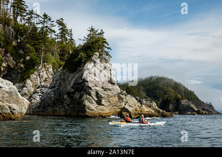 Kayaker paddeln unter den gebrochenen Gruppe Inseln im Pacific Rim National Park Reserve, British Columbia, Kanada. Stockfoto