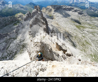 Jungen gutaussehenden männlichen Bergsteiger auf einem steilen und exponierten Fels klettert ein Klettersteig in Alta Badia in Südtirol Stockfoto